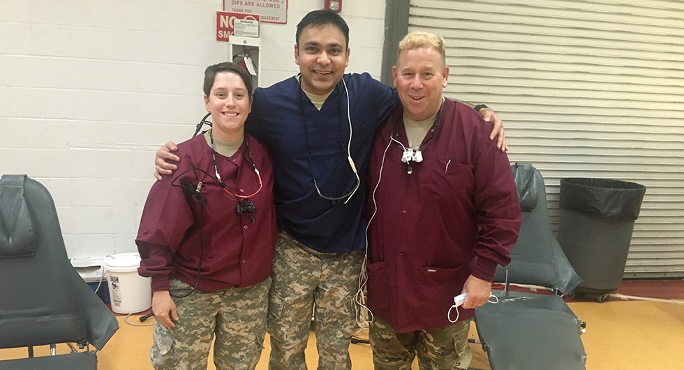 Dentist and two team members wearing scrubs and military camoflage