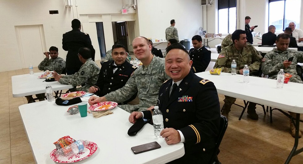 Group of people in military uniforms eating a meal together