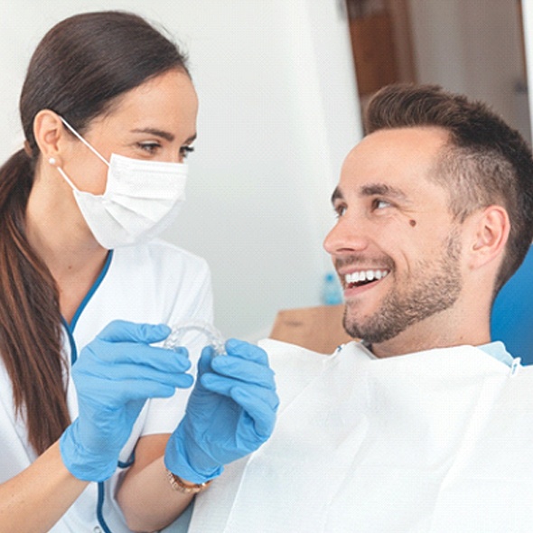 Dentist smiling while discussing cost of Invisalign in Virginia Beach