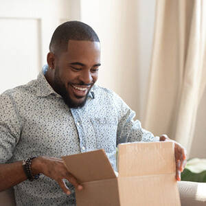 Smiling man sitting on couch opening a package